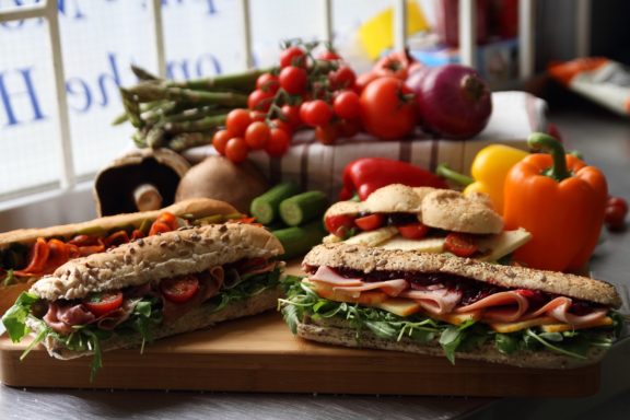 Side view of rustic sandwiches with vegetables in the background, captured by Elizabeth Wood, specializing in food photography.
